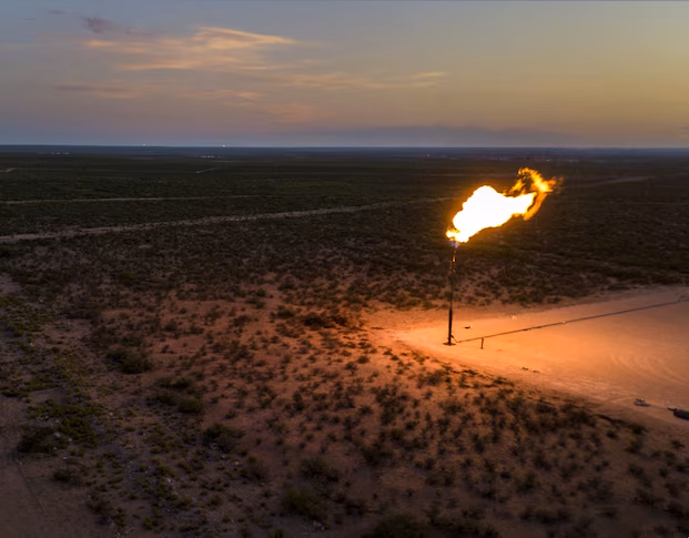 Gas flare burning at dusk on a remote scrubland oil and gas site — stranded energy Kala Data converts into revenue